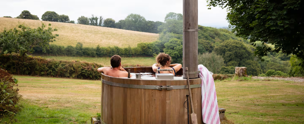 two people in a wood fired hot tub looking out over fields
