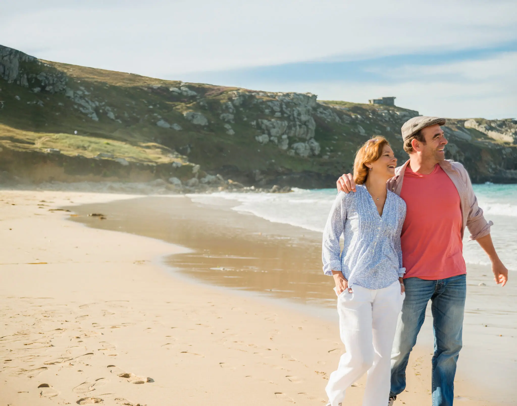 Couple walking on a beach near their holiday let in Devon