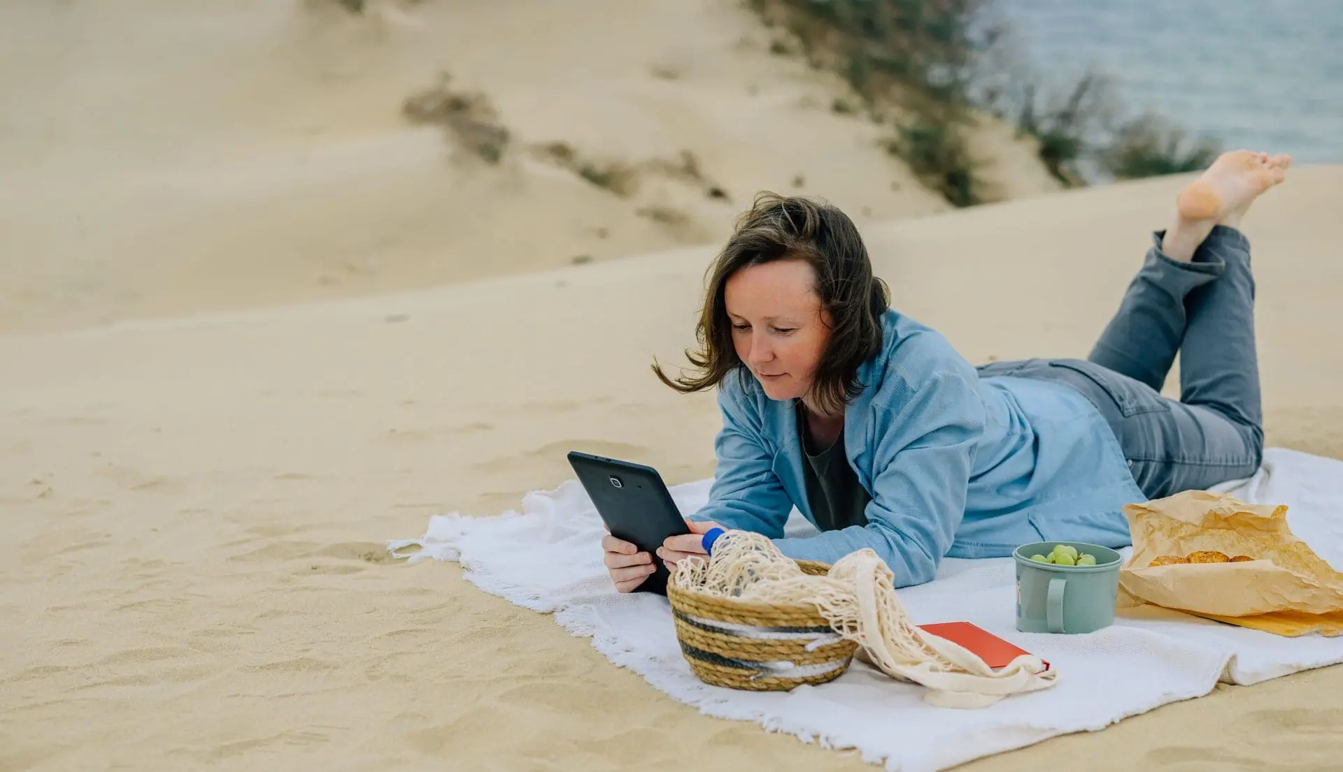 Woman on beach reading guides on tablet