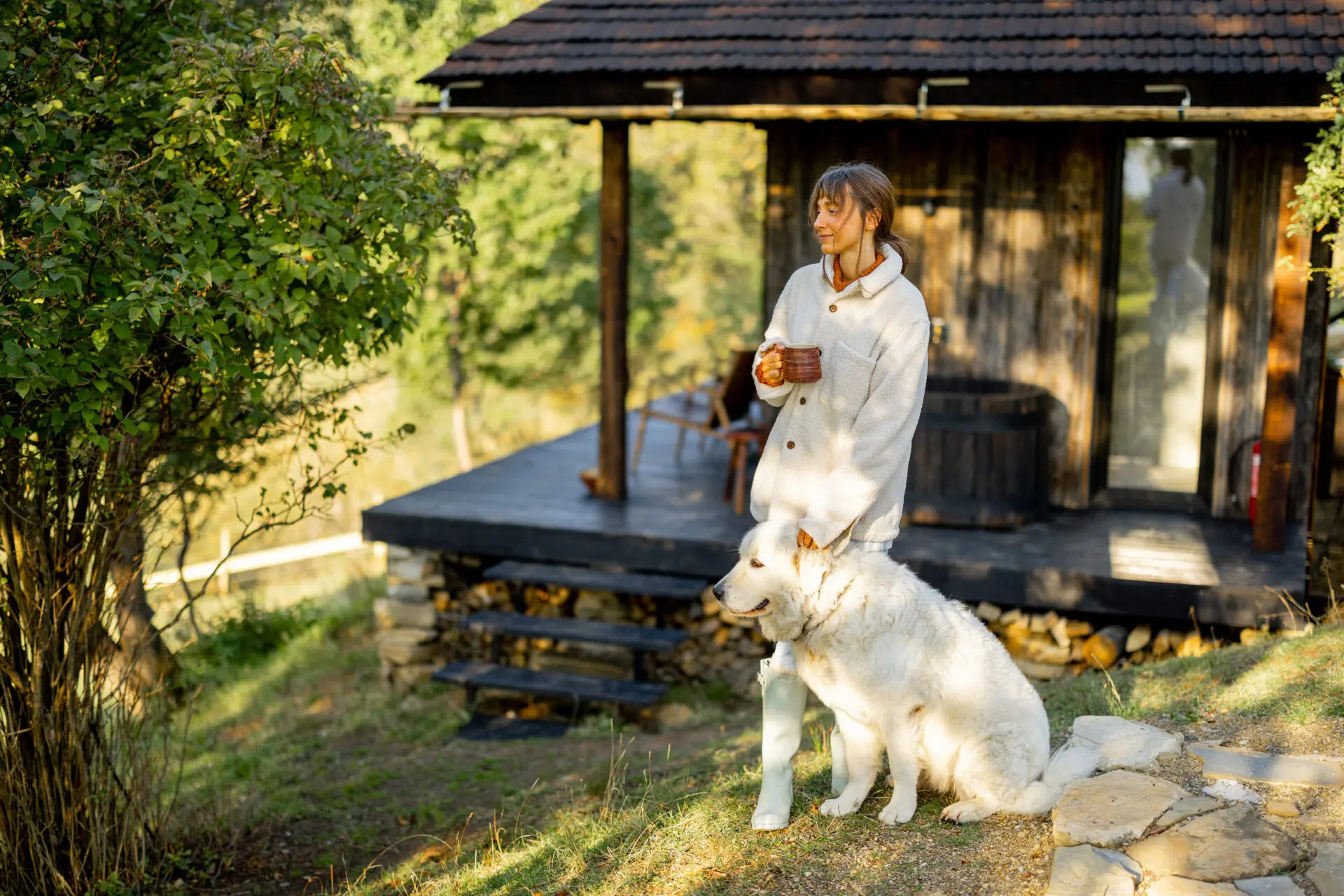 Woman enjoy her coffee outside her cottage with her dog