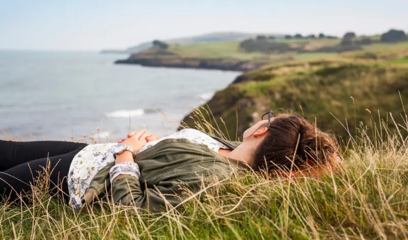 Woman relaxing on cliff top as she earns from a co-host