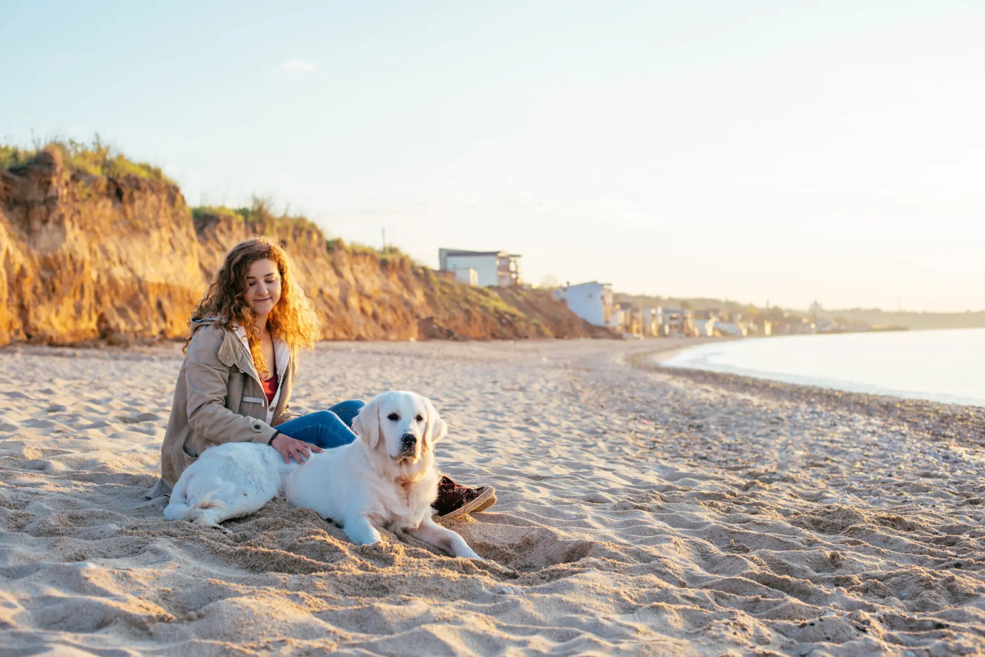 Woman sitting with dog on the beach