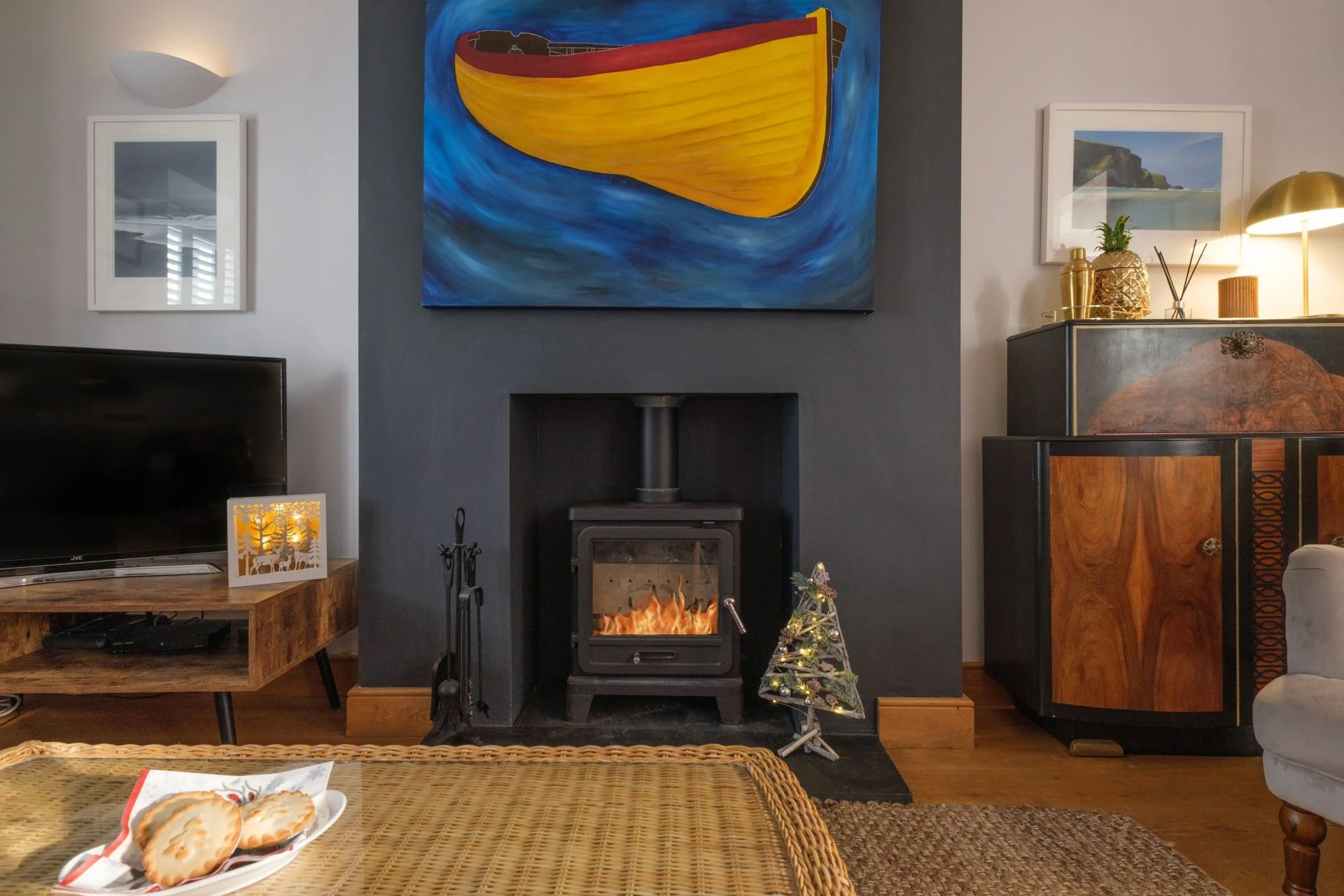 Sitting room at Crowthers Hill with a wood burner and a painting of a yellow boat