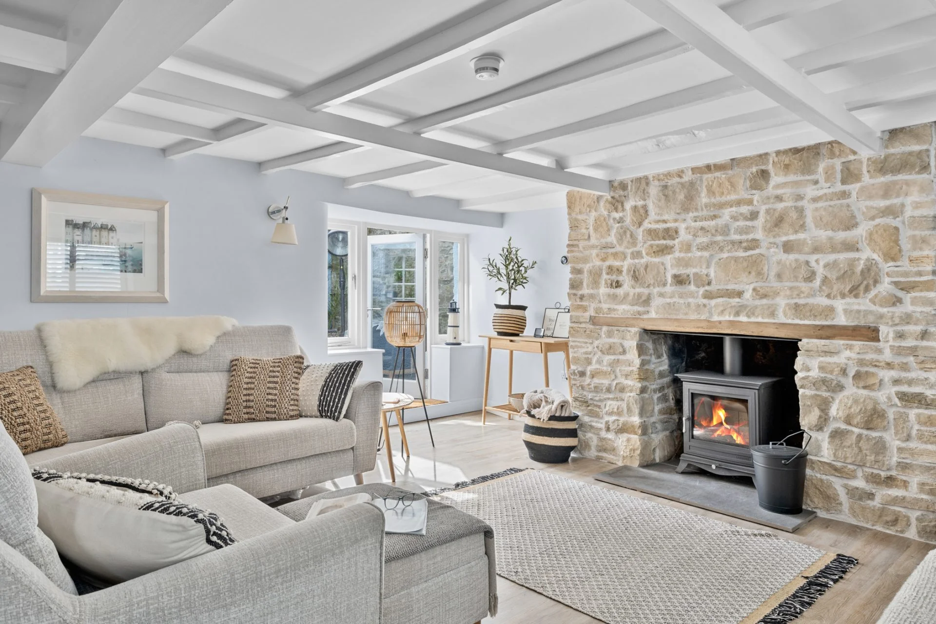 Sitting room at Quay Cottage with a wood burner set into an exposed stone chimney breast