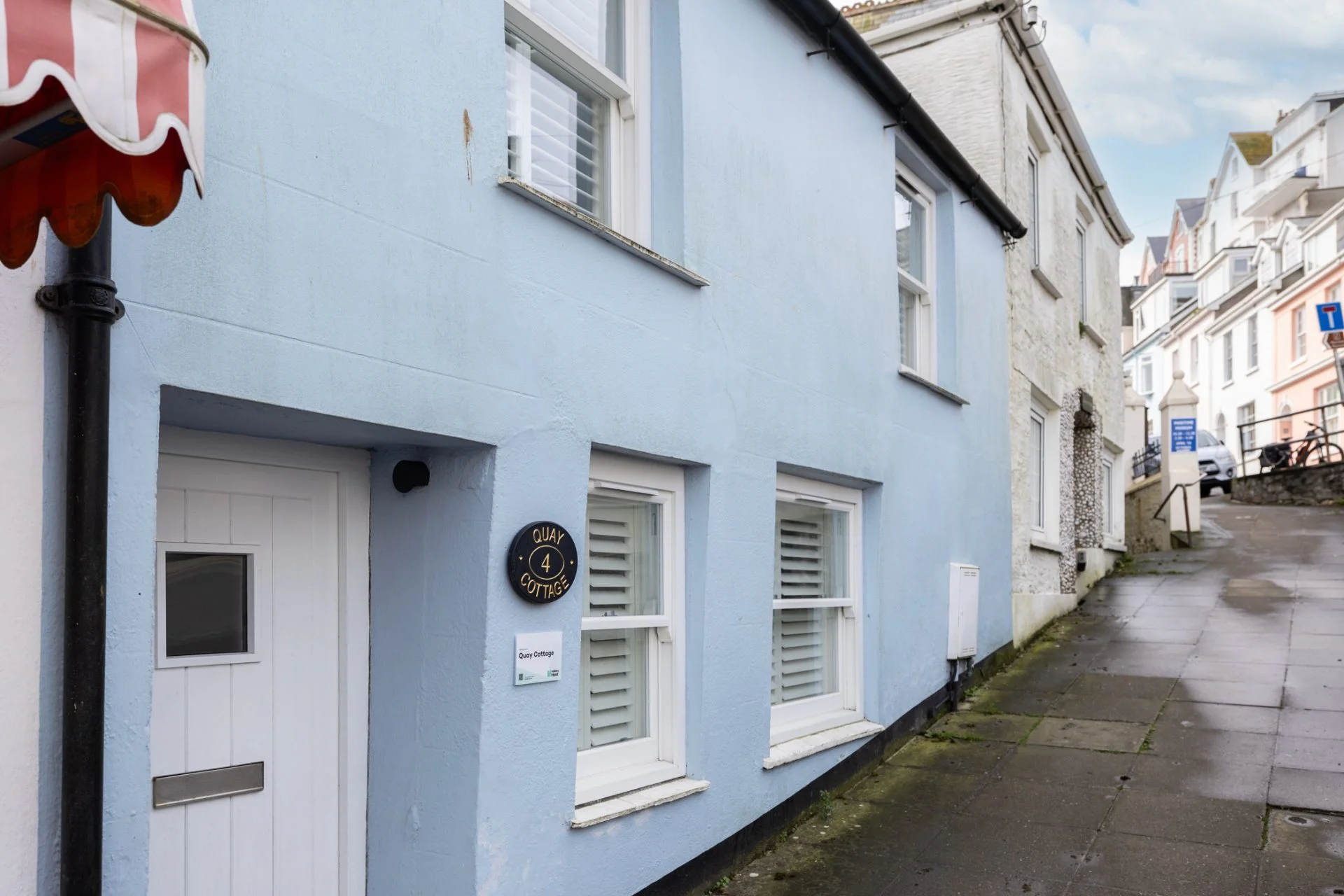 The pale blue front of Quay Cottage on a Salcombe street