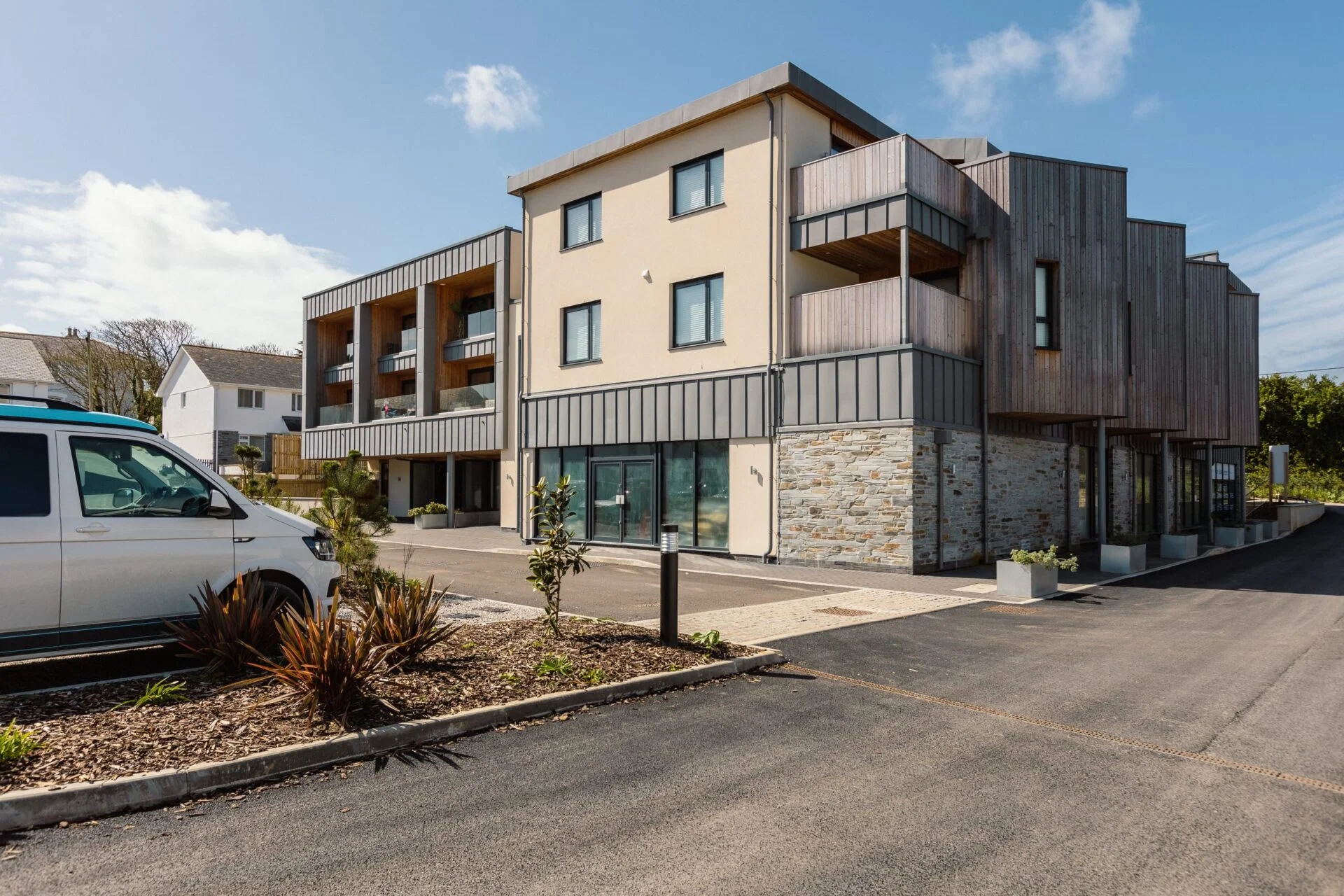 Outside Harlyn Digs in Harlyn Bay, a modern building with timber cladding, stone walls and balconies