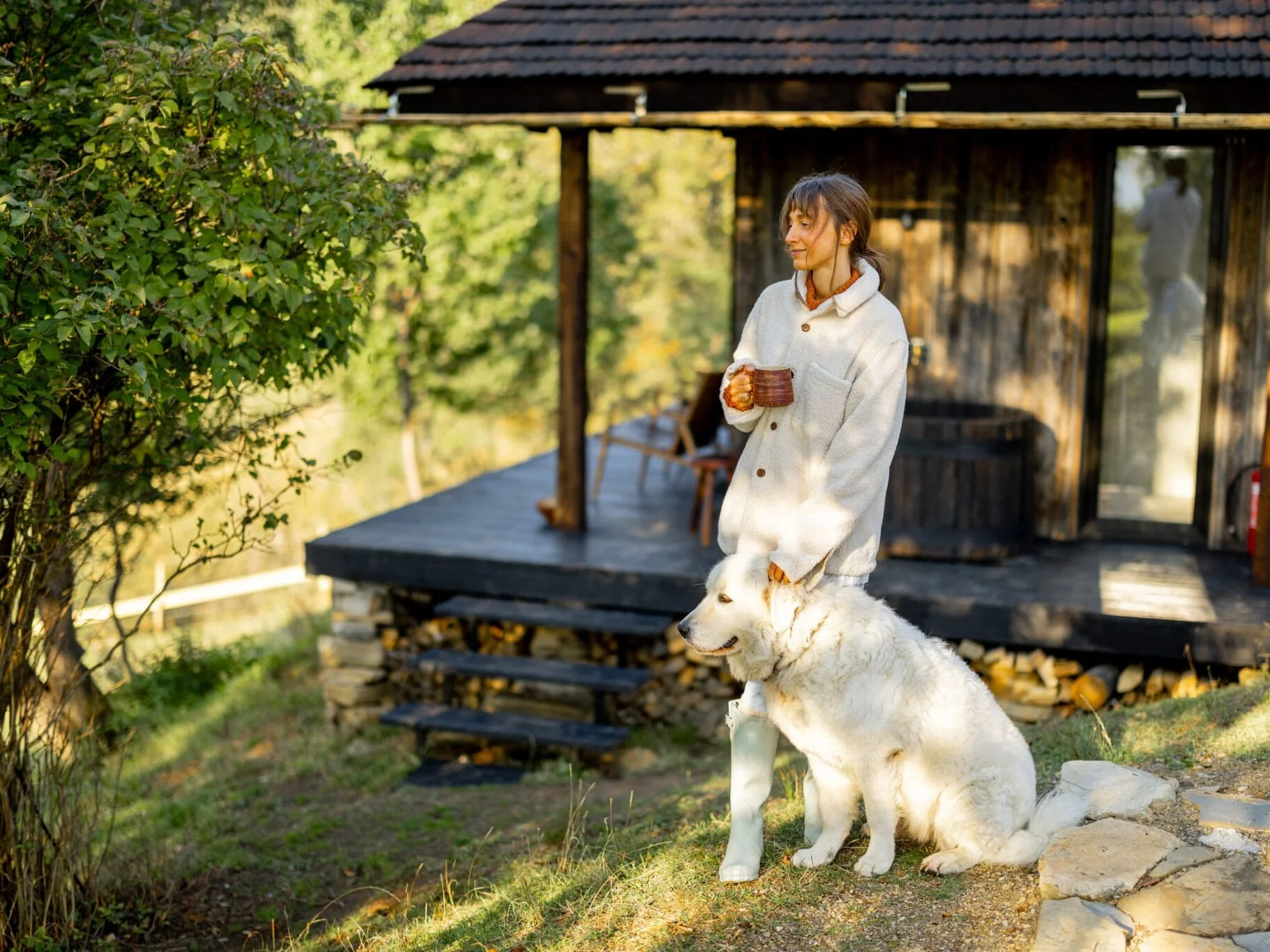 Woman enjoy her coffee outside her cottage with her dog