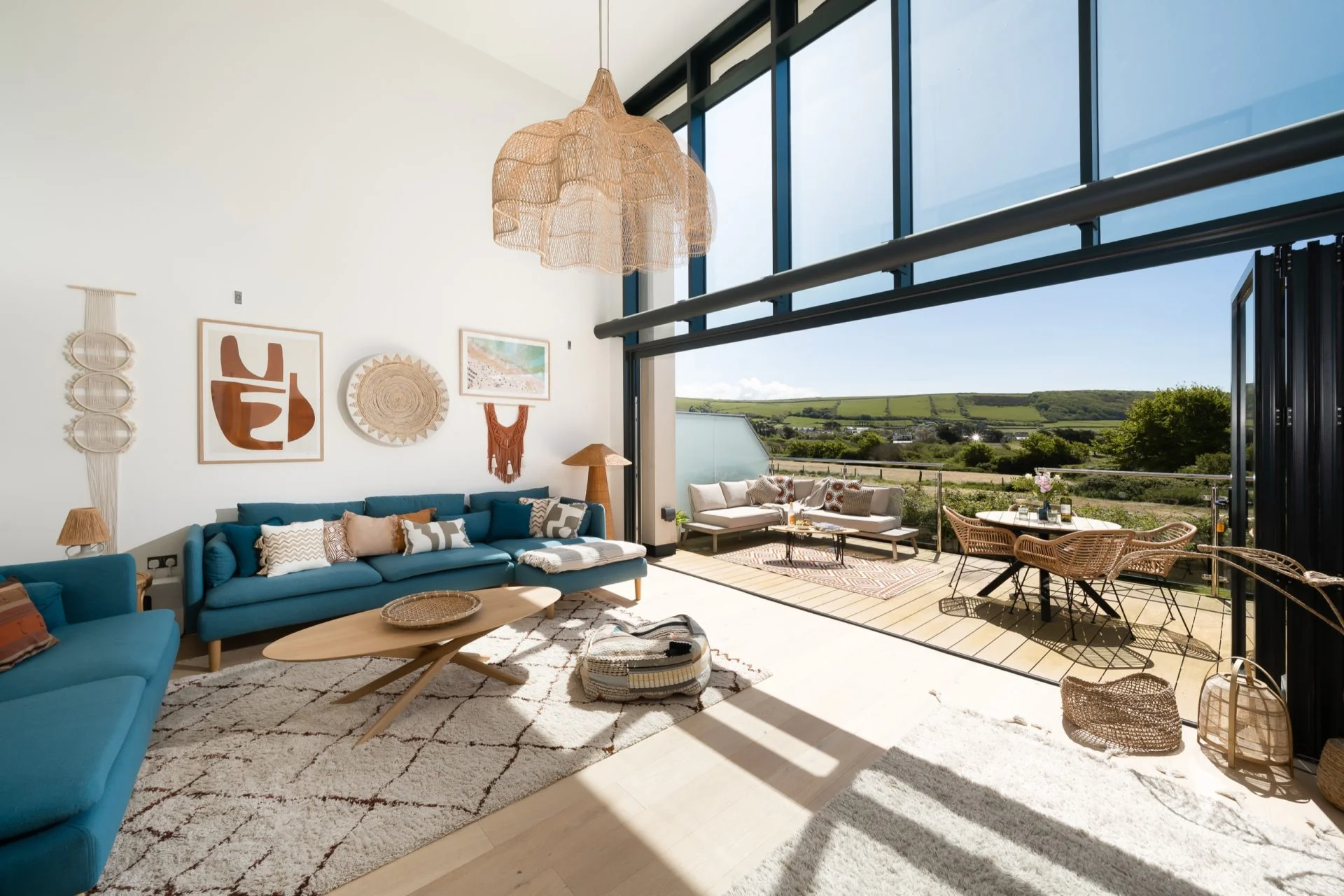 The living room of a holiday home opening onto a terrace with countryside views.