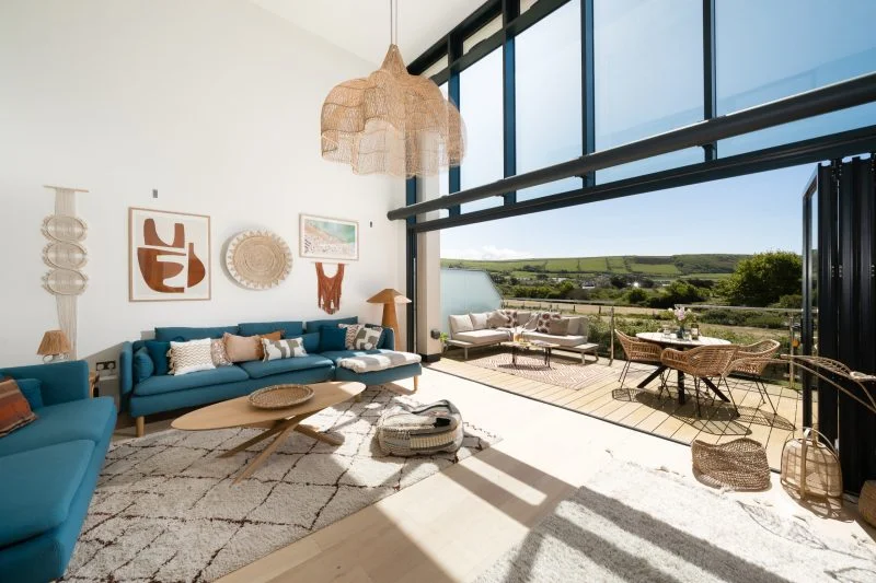 The living room of a holiday home opening onto a terrace with countryside views.